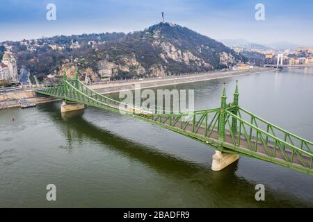 Budapest, Hongrie - vue aérienne sur le pont de la liberté (Szabadsag hid) le matin du printemps avec des trams jaunes et la Statue de la liberté en arrière-plan. bri vide Banque D'Images