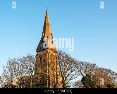 La broche de l'église Sainte-Trinité au-dessus des treetops illuminés par le soleil couchant dans le Yorkshire de Knaresborough Angleterre Banque D'Images