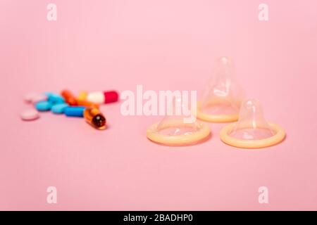 Focalisation sélective des préservatifs et des pilules contraceptives sur le fond rose Banque D'Images