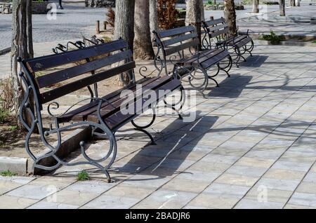 Bancs vides sur une place de la ville. Une rangée de bancs de rue vides dans une ville ensoleillée de printemps. Une journée de printemps chaude dans une ville européenne sans peuple. Le silence A Banque D'Images