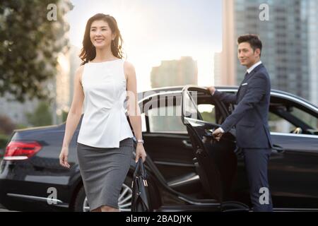 Une femme d'affaires chinoise confiante qui sort de sa voiture Banque D'Images