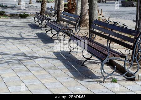 Bancs vides sur une place de la ville. Une rangée de bancs de rue vides dans une ville ensoleillée de printemps. Une journée de printemps chaude dans une ville européenne sans peuple. Le silence A Banque D'Images