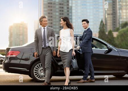 Des hommes d'affaires chinois confiants sortent de leur voiture Banque D'Images