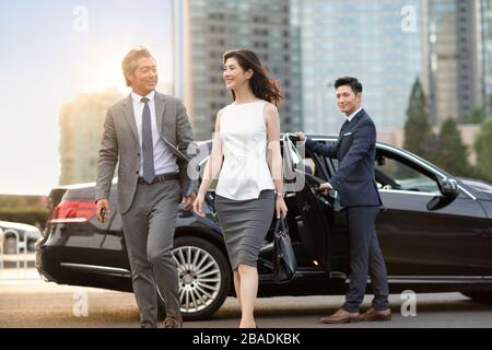 Des hommes d'affaires chinois confiants sortent de leur voiture Banque D'Images