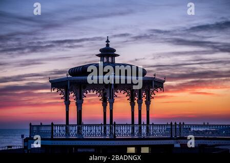 Brighton, Royaume-Uni, le 26 mars 2020, le soleil se couche derrière le kiosque à bande sur le front de mer de Hove ce soir alors que le pays s'isole contre le coronavirus. Banque D'Images
