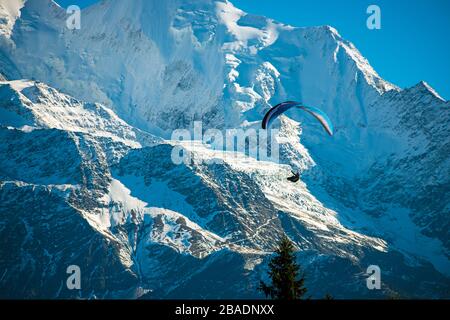 Un parapente en parapente dans les Alpes françaises près du Mont Blanc - montagnes enneigées énormes, ciel bleu et parapente. Scène très excitante. Banque D'Images