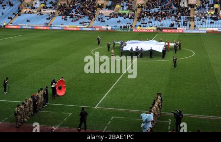 Les membres des forces armées tenant un grand maillot de Coventry City dans le cercle central et aligné sur le côté du terrain se préparant pour le procès-verbal silence Banque D'Images