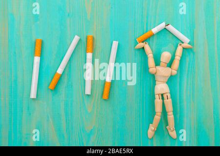 Cesser de fumer - homme en bois écrasant les cigarettes Banque D'Images