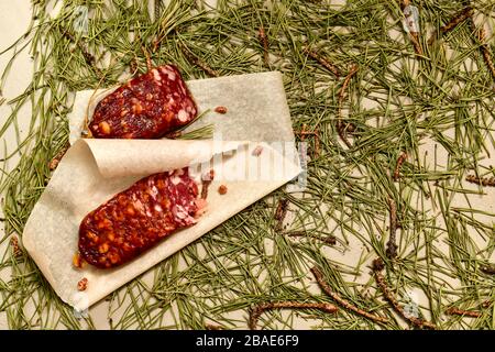 Saucisse séchée faite de viande de castor coupée avec des tranches de parchemin avec des bourgeons de pin sur le plancher gauche fait d'aiguilles de pin. Banque D'Images