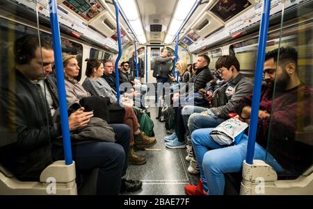 Les passagers du métro londonien. Vue intérieure d'un train de métro très animé de la ligne Piccadilly de Londres rempli de voyageurs et de touristes. Banque D'Images