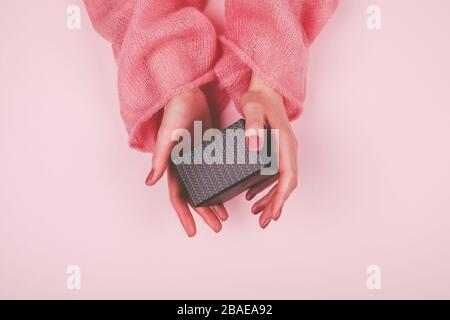 Femme mains avec manucure rose tenir boîte cadeau noire Banque D'Images
