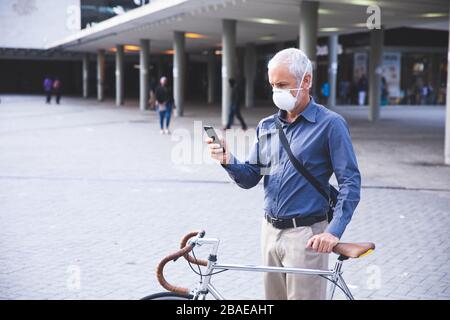 Homme d'âge moyen portant un masque Covid 19 au coronavirus lors de vos déplacements Banque D'Images