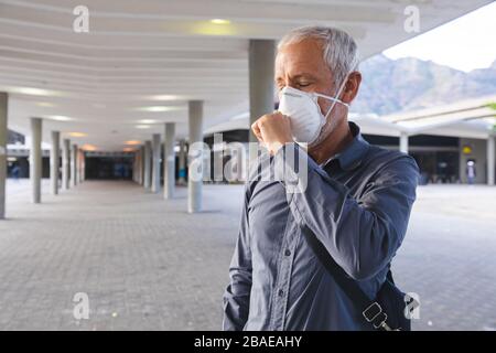 Homme d'âge moyen portant un masque de Covid19 à Coronavirus toussant Banque D'Images