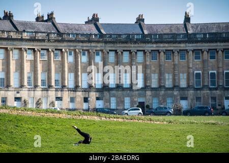 Une femme fait du yoga devant le Royal Crescent à Bath, après que le gouvernement a annoncé des restrictions strictes pour ralentir la propagation du Coronavirus. Banque D'Images