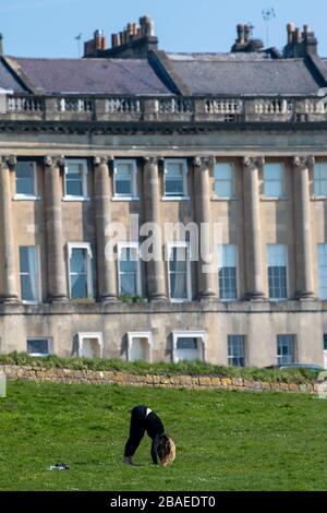 Une femme fait du yoga devant le Royal Crescent à Bath, après que le gouvernement a annoncé des restrictions strictes pour ralentir la propagation du Coronavirus. Banque D'Images