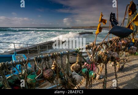 Alors que les vagues de couchers de soleil s'écrasent sur les rochers près de Sennen Harbour, Océan Atlantique Cornwall West Country Angleterre Royaume-Uni GB Banque D'Images