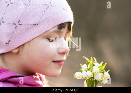 Portrait d'une jeune fille heureuse tenant un bouquet de fleurs de neige printanière plein air. Banque D'Images