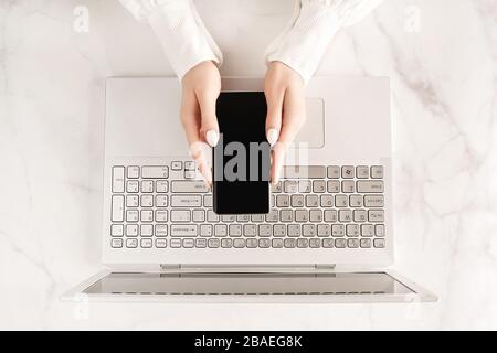 Belles mains pour Femme avec smartphone et ordinateur portable à jour sur fond de marbre. Concept d'entreprise pour femme. Concept de travail à domicile. Maquette pour vous Banque D'Images