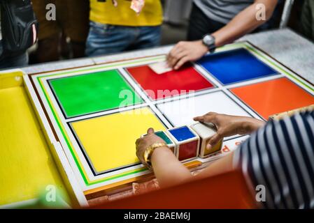 Divers handspeoples jouant sur un jeu de chance aux Philippines. Cubes rouge, vert, am, jaune, blanc, bleu et orange. Banque D'Images