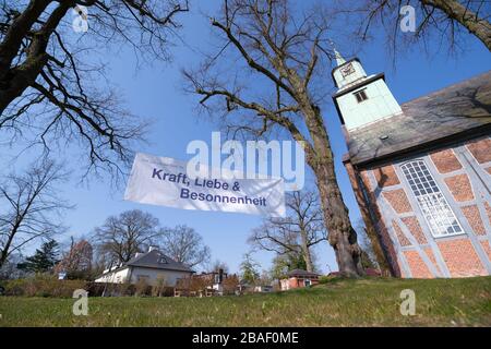 Hambourg, Allemagne. 27 mars 2020. Une bannière avec l'inscription "Dieu nous donne l'esprit de force, d'amour et de prudence" pend entre deux arbres devant l'église de Nienstedtener. Parce que les affaires normales d'église sont suspendues par le virus corona, le district d'église de Hambourg-Ouest a imprimé des affiches pour ses congrégations avec des mots encourageants pour raccrocher devant les églises. Crédit: Jonas Walzberg/dpa/Alay Live News Banque D'Images