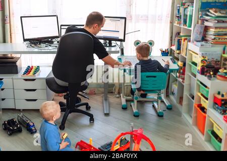 Père avec enfants essayant de travailler de la maison pendant la quarantaine. Restez à la maison, travaillez à partir du concept de maison pendant la pandémie de coronavirus Banque D'Images