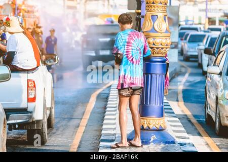 Un jeune photographe en vêtements mouillés utilise un appareil photo reflex numérique pour prendre des photos du festival d'éclaboussures d'eau Songkran sur la route dans la ville. Banque D'Images