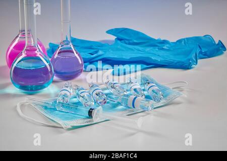 Trois flacons médicaux avec réactifs chimiques violets et roses. Ampoules Mockup, gants jetables bleus, seringue et masque isolés sur blanc. Laboratoire r Banque D'Images