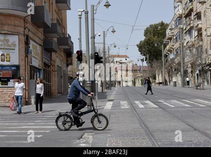 Jérusalem, Israël. 27 mars 2020. Un israélien porte un masque protecteur tout en faisant du vélo dans une rue vide de Jérusalem, le vendredi 27 mars 2020. Onze Israéliens sont morts du coronavirus, alors que plus de 3 000 ont été diagnostiqués avec la maladie. Le gouvernement israélien a imposé de sévères restrictions de mouvement, laissant seulement des magasins essentiels ouverts dans un effort pour arrêter la propagation du coronavirus. Photo par Debbie Hill/UPI crédit: UPI/Alay Live News Banque D'Images