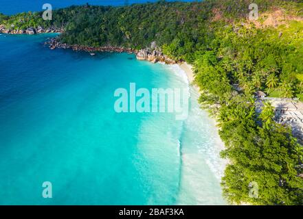 Vue aérienne par drone de la plage d'Anse Lazio courbant le long d'un promontoire boisé avec de l'eau turquoise, île de Praslin, Seychelles Banque D'Images