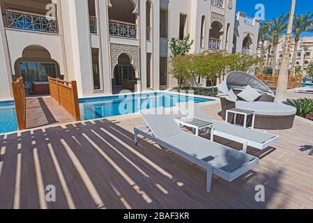 Chaises longues dans la luxueuse salle de villégiature tropicale de l'hôtel terrasse près de la piscine avec pont Banque D'Images