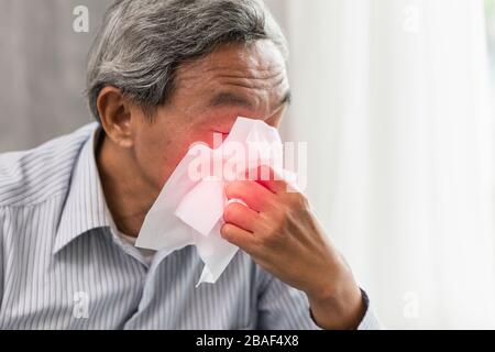 Le vieil homme asiatique tombe malade de la grippe et du nez liquide lorsque la saison change et signe du virus corona (Covid-19). Banque D'Images