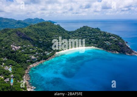 Vue aérienne drone de la plage isolée d'Anse petite avec promontoire boisé et océan Indien turquoise, Mahé, Seychelles Banque D'Images