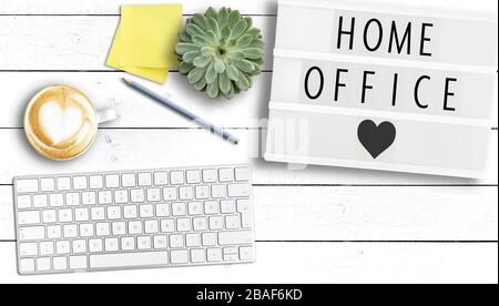 Text HOME OFFICE sur la visionneuse sur table en bois avec clavier d'ordinateur, notes adhésives et tasse de café, travaillant de la maison pendant la pandémie de coronavirus Banque D'Images