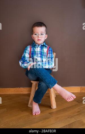 Jeune enfant souriant avec chemise bleue et bretelles Banque D'Images