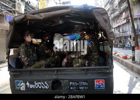 Dhaka, Bangladesh. 27 mars 2020. Les soldats de l'armée conscients que les gens en général utilisent le masque, restent à la maison lorsqu'ils patrouillent le long d'une rue lors d'un verrouillage imposé par le gouvernement comme mesure préventive contre le coronavirus COVID-19 à Dhaka le 27 mars 2020. Crédit: Alay/Alay Live News Banque D'Images