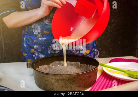 Cuisson Ingrédients et ustensiles pour la cuisson gâteau éponge. Gâteau éponge de cuisson. Une femme verse la pâte dans un moule à pâtisserie. Banque D'Images