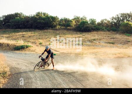 Le cycliste mâle glisse la poussière sur le vélo en gravier Banque D'Images