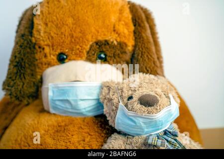 Deux ours en peluche marron, petits et grands, portent des masques bleus de protection pour des raisons de santé Banque D'Images