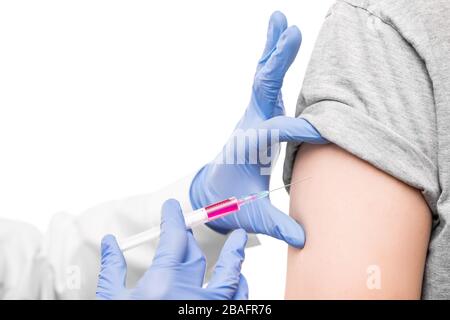 Les mains gantées de l'infirmière dans la seringue de maintien du blancoat avec vaccin contre le covid19 par l'épaule du malade avant de faire l'injection Banque D'Images