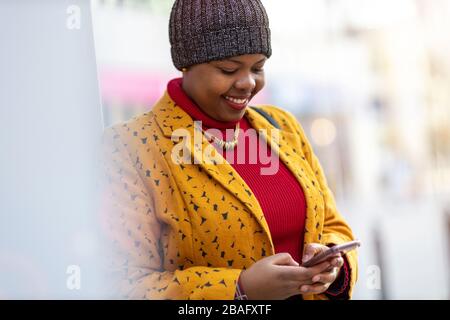 Jeune femme avec smartphone dans un quartier urbain Banque D'Images