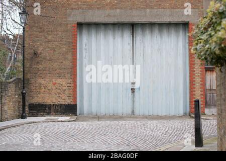 Grandes / grandes portes concertina bleu gris à une usine ou un entrepôt dans une rue arrière à Londres Angleterre Royaume-Uni Banque D'Images
