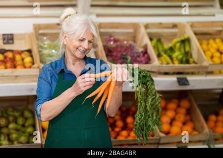 Femme senior travaillant dans une petite épicerie Banque D'Images