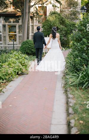 La mariée et le marié posent sur la main. Au coucher du soleil, sur le lieu du mariage. La mariée tient une fleur de mariée dans sa main. Banque D'Images