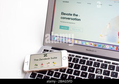 Les icônes de l'application mobile Zendesk support Suite sont visibles sur un smartphone avec la page Web Zendesk en arrière-plan. Banque D'Images