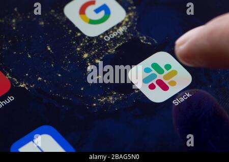Gros plan de l'icône de l'application mobile Slack sur un iPad et d'un doigt l'ouvrant. Slack est un logiciel B2B, un outil de messagerie de poste de travail, un outil de communication d'équipe ou une plate-forme. Banque D'Images