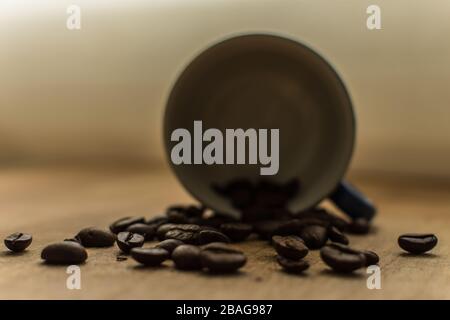 Grains de café sur une table en bois avec une tasse au fond Banque D'Images