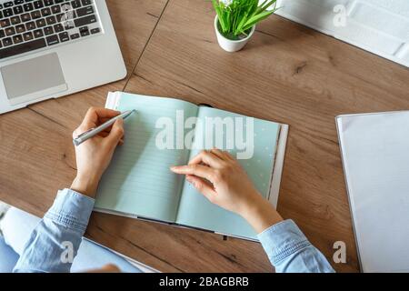 Gros plan sur la fille africaine écrit des notes dans le carnet d'agenda à la table. Banque D'Images