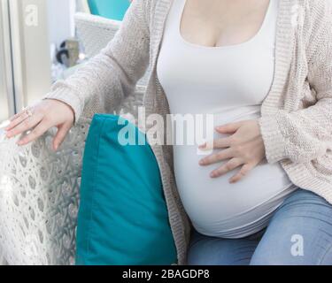 Femme enceinte en chemise blanche tenant main sur son ventre Banque D'Images