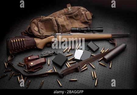 Carabine moderne boulonné et cartouches pour elle sur une table en bois sombre. Fusil à lunette de tir sur un fond sombre. Des armes pour la chasse, un sport Banque D'Images