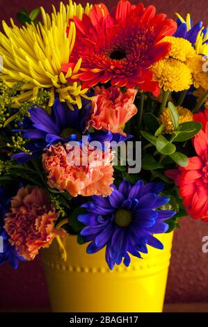 Fleurs multicolores, y compris mamans, chrysanthèmes, œillets dans un seau jaune Banque D'Images